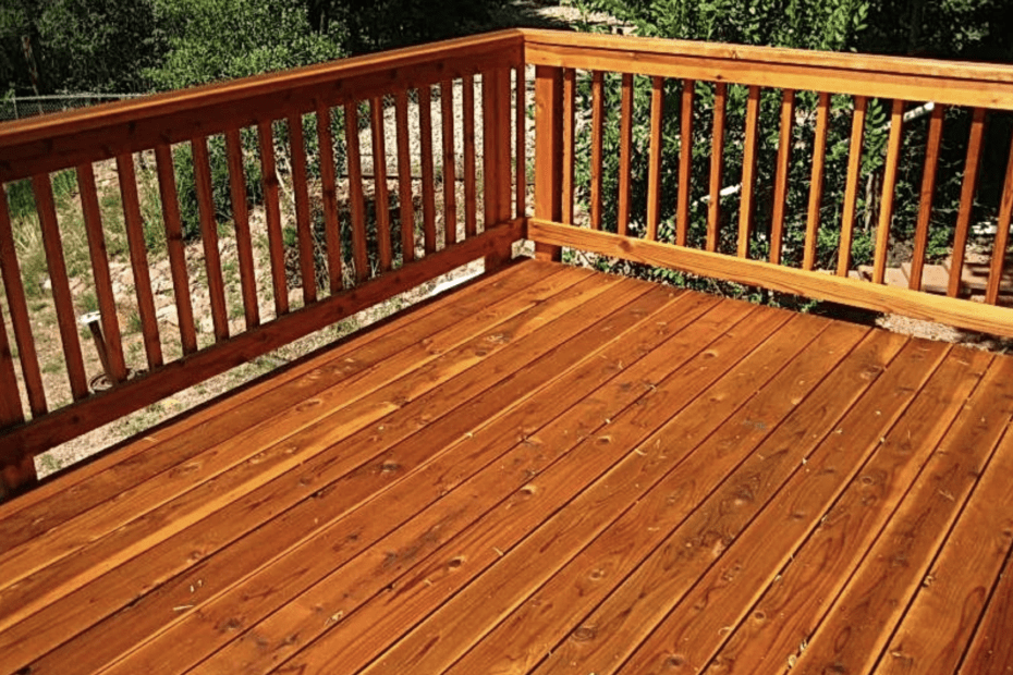 Dark brown stained wooden deck with trees in the background