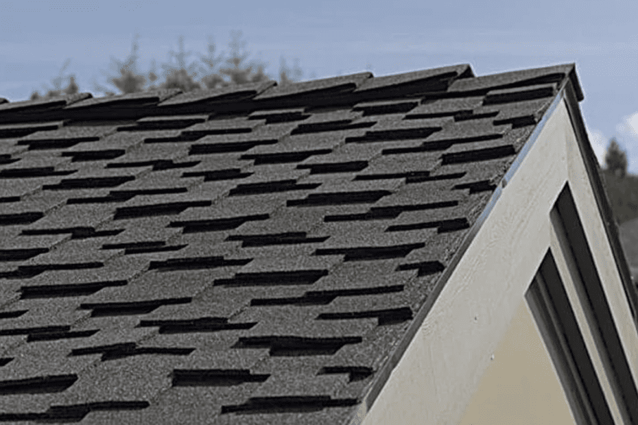 Lifted gray shingles on a light yellow house roof