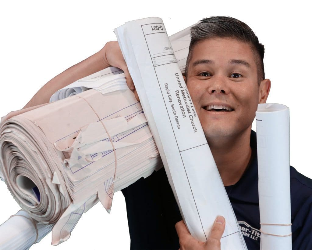 smiling man with spiked gray hair holding architectural blue prints