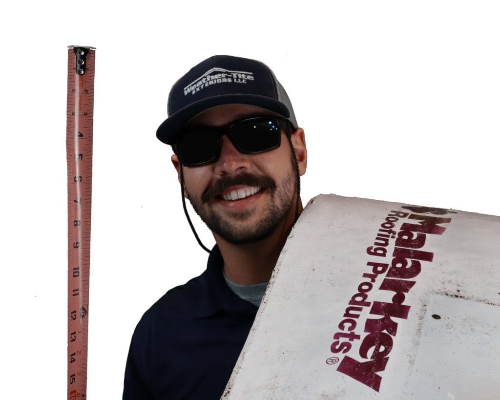 smiling man with dark brown beard holding a roofing mat and tape measurer