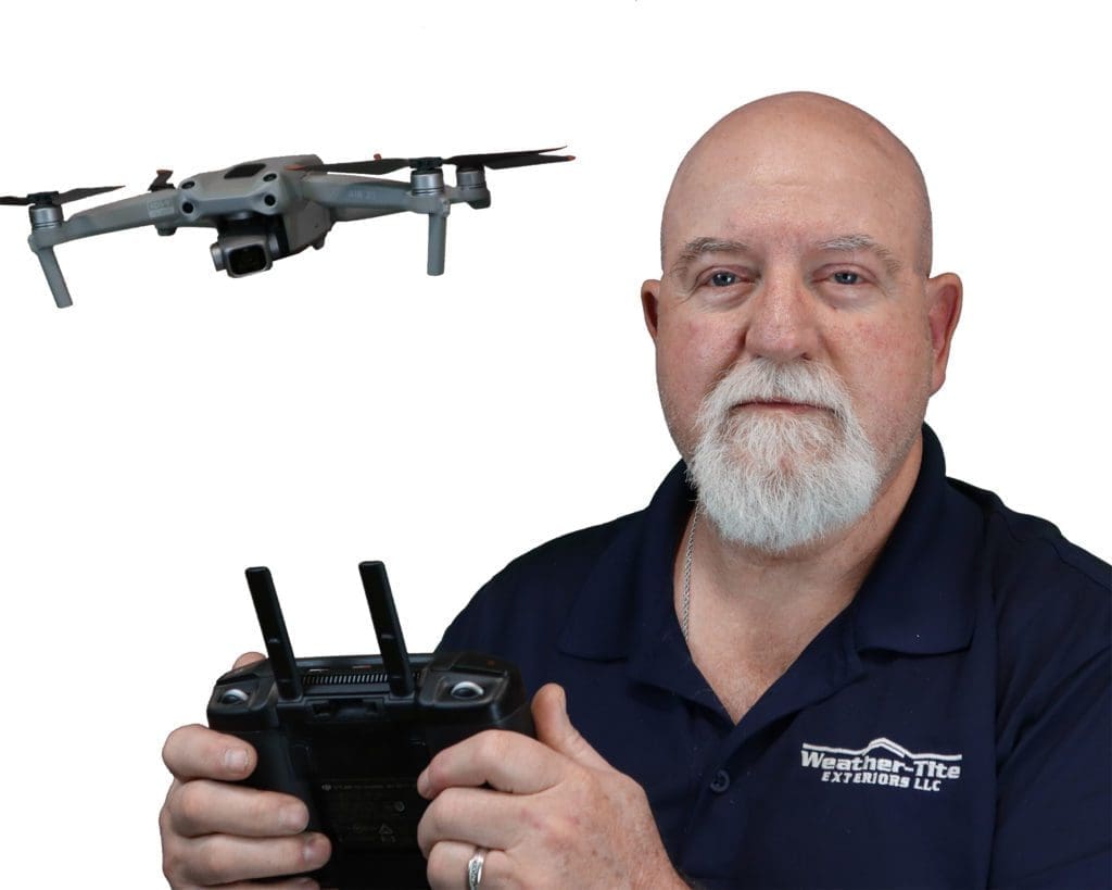 bald man with white goatee flying a drone behind him