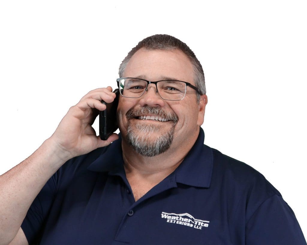 smiling man with short gray hair and glasses talking on a phone