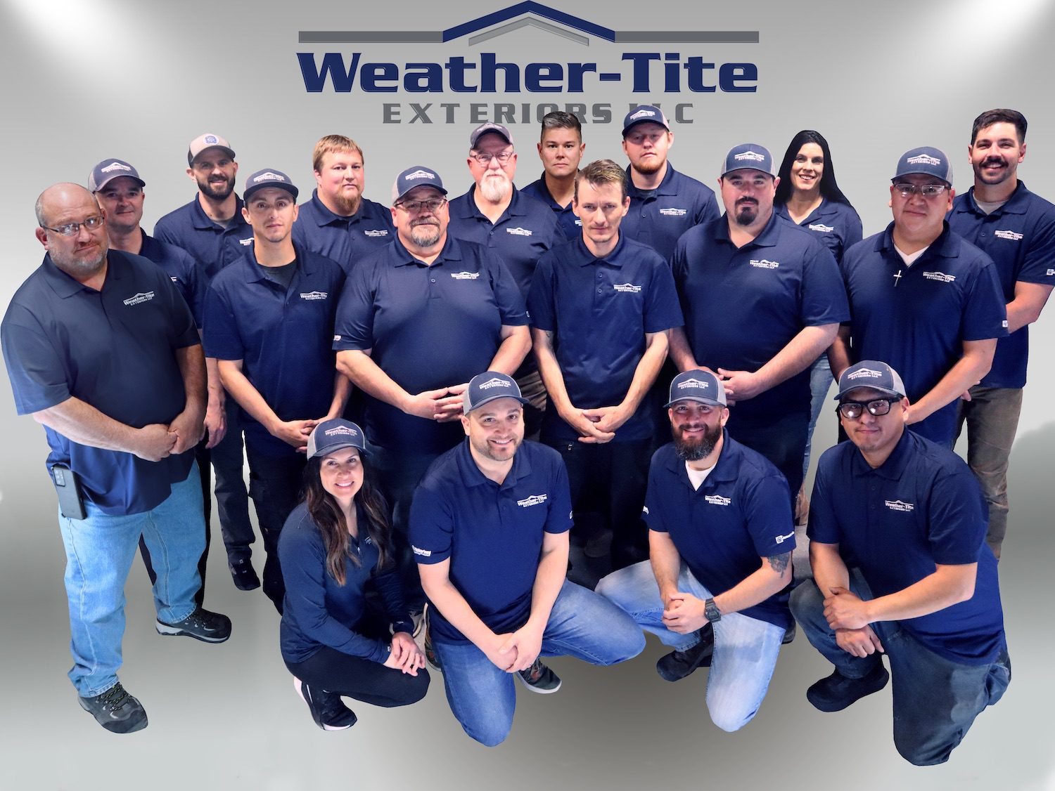 group of people all wearing weather tite shirts and hats posing in front of the weather tite logo with a silver background
